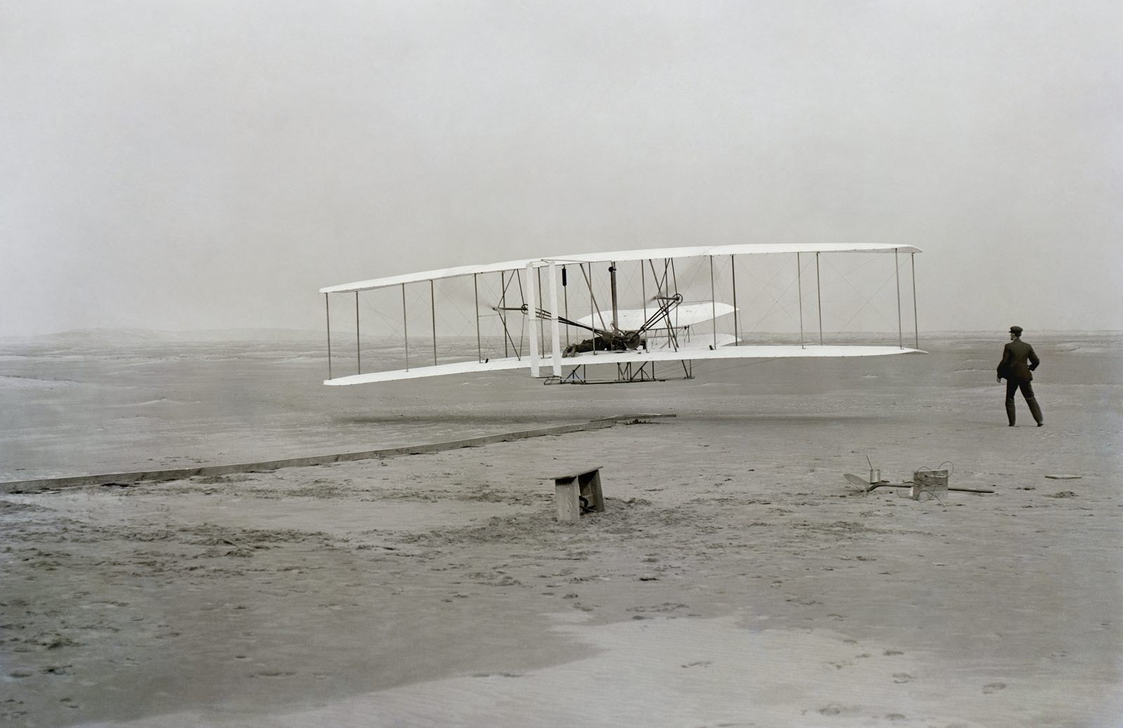 The Wright Flyer lifting off at Kitty Hawk on December 17, 1903, Orville at the controls and Wilbur running at the wingtip.