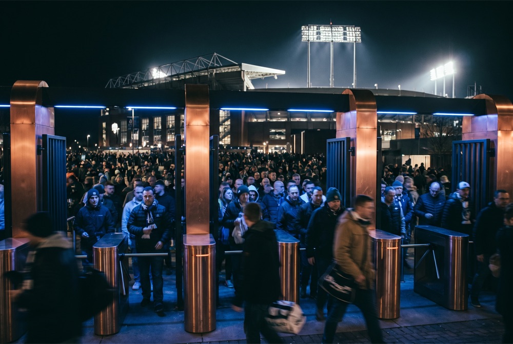 A crowd entering a stadium through modern smart entry gates at night