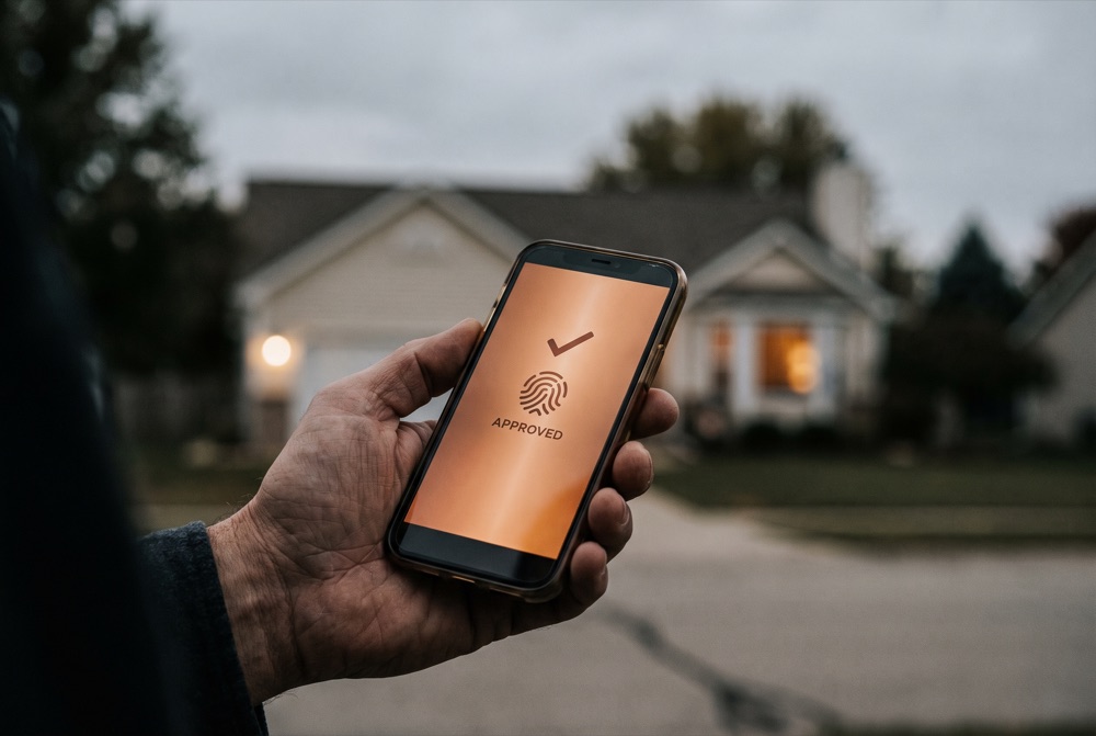 A phone showing an insurance claim approved in seconds outside a home