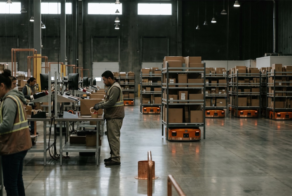 A fulfillment warehouse with orange robotic drive units carrying shelves