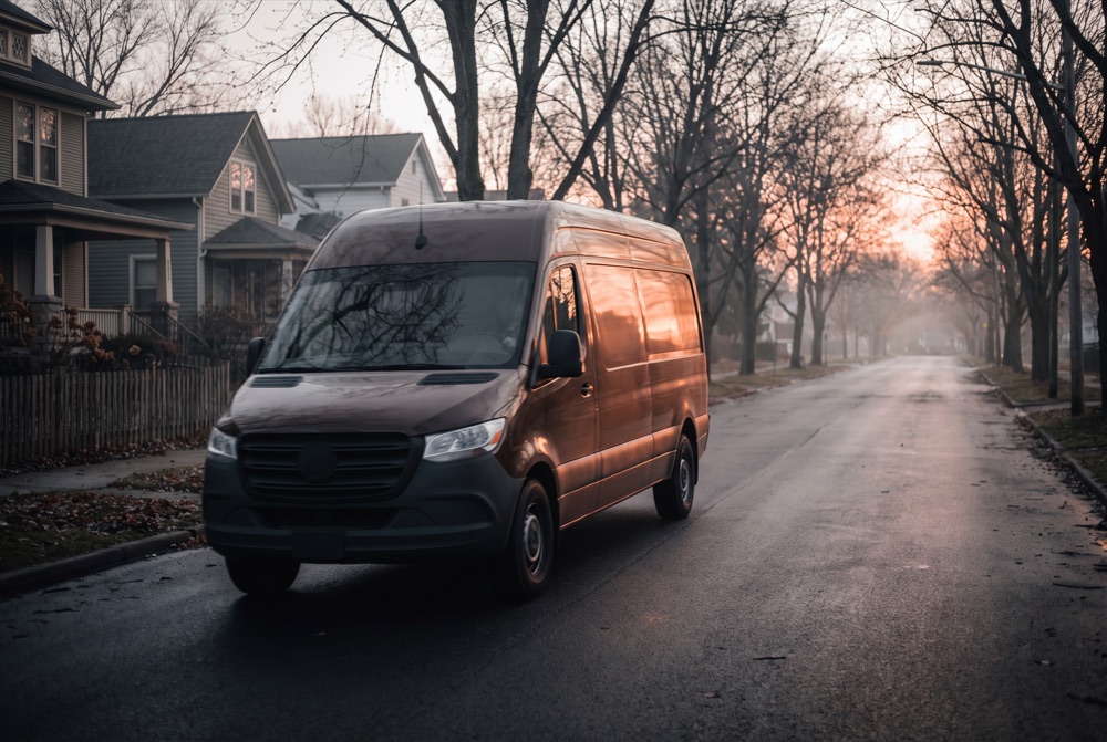 A brown parcel delivery van on an optimized route at dawn